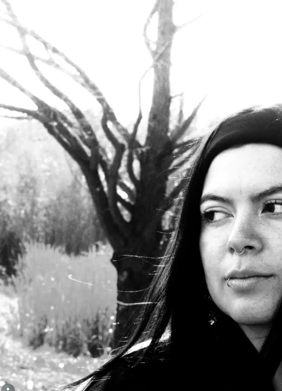 Retrato en blanco y negro de una mujer junto a un árbol seco