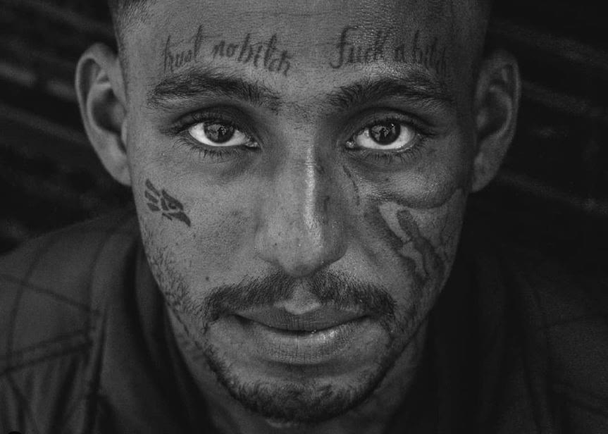 Mírate en mis ojos: retrato en blanco y negro de un hombre con tatuajes en el rostro