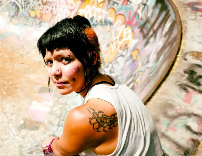 Joven con un tatuaje en el hombro en un skatepark con grafiti